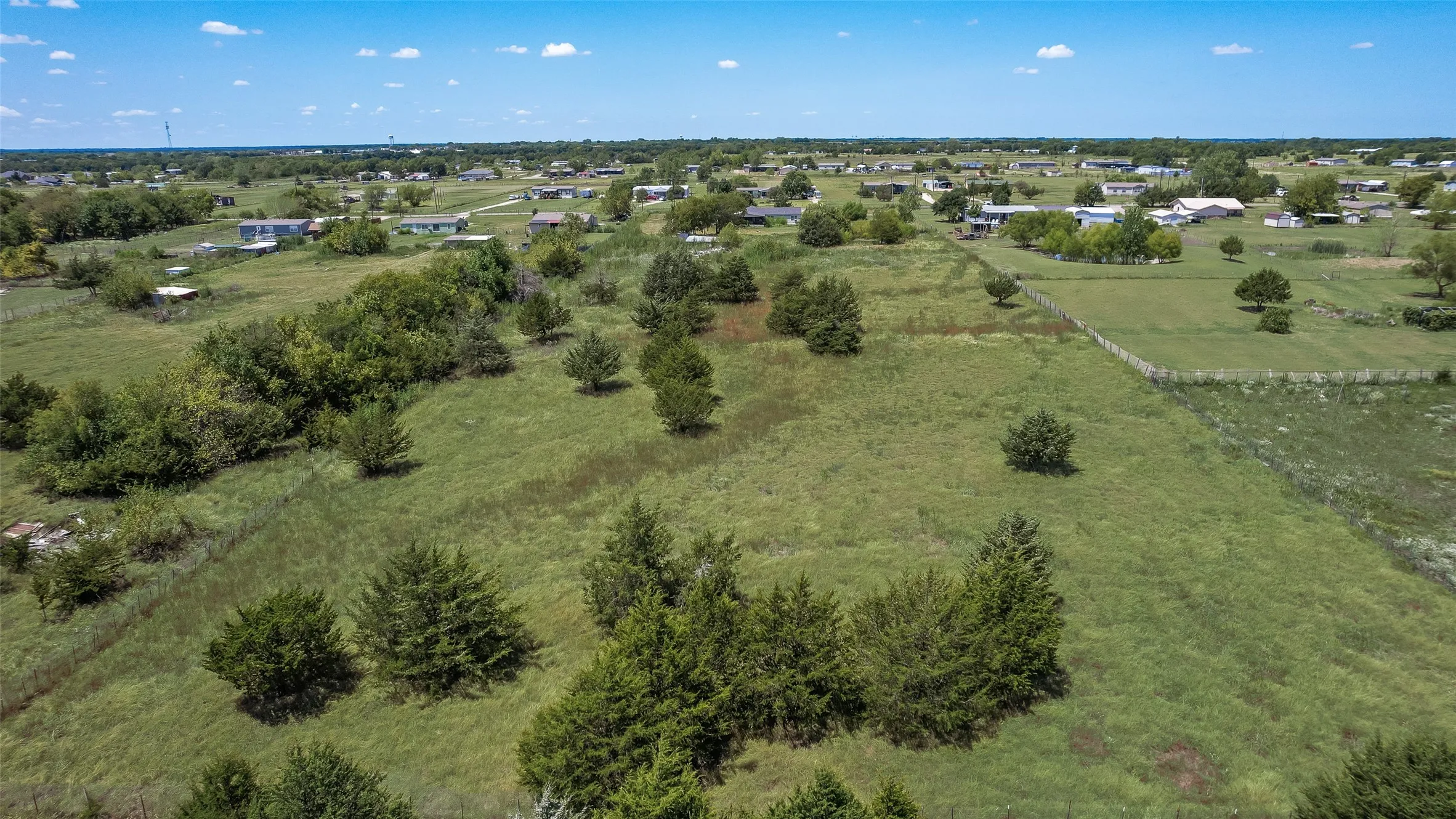 Expansive undeveloped land featuring natural grasses and scattered mature trees