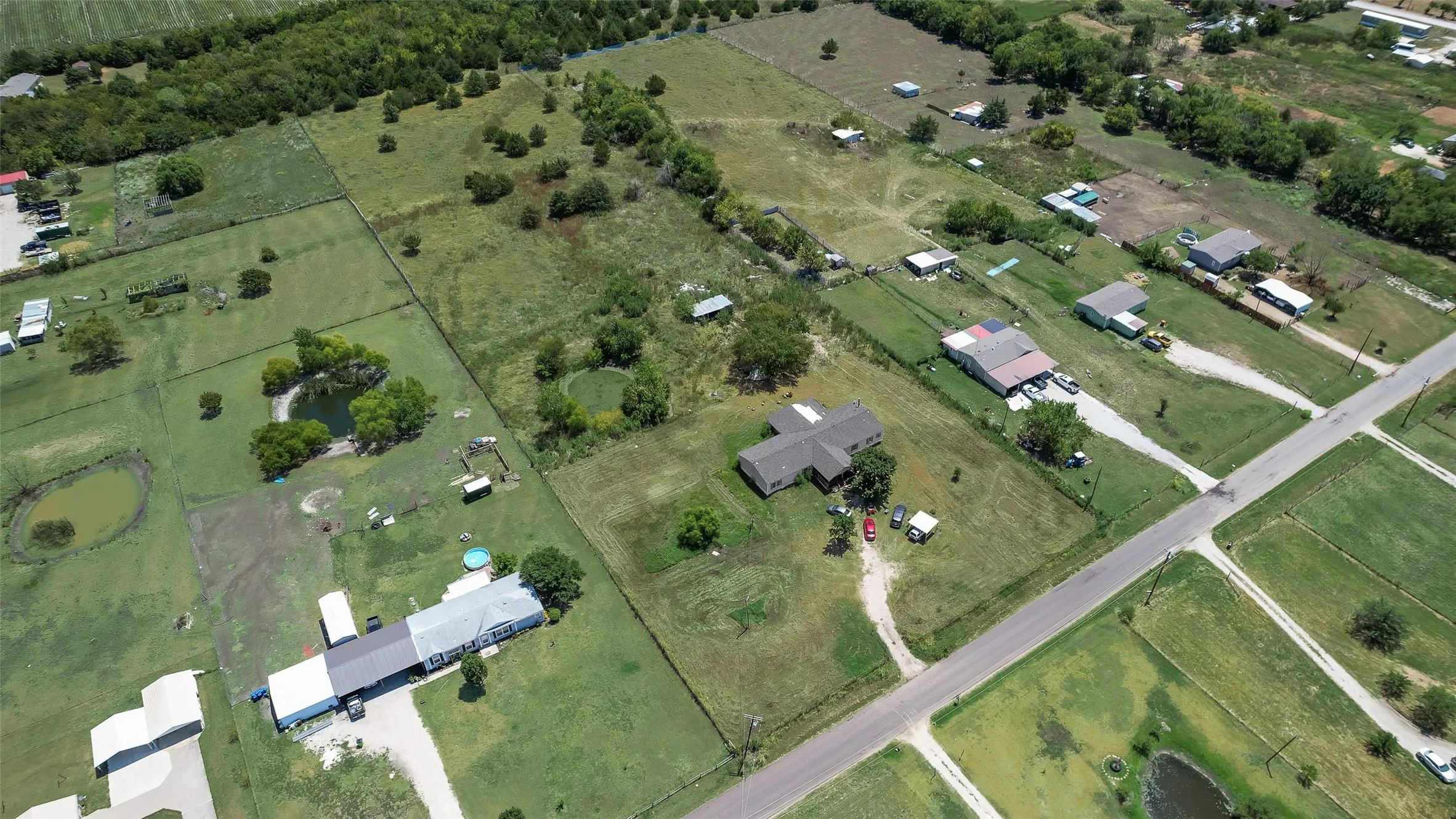 Multiple residential structures, expansive green spaces, and a paved road