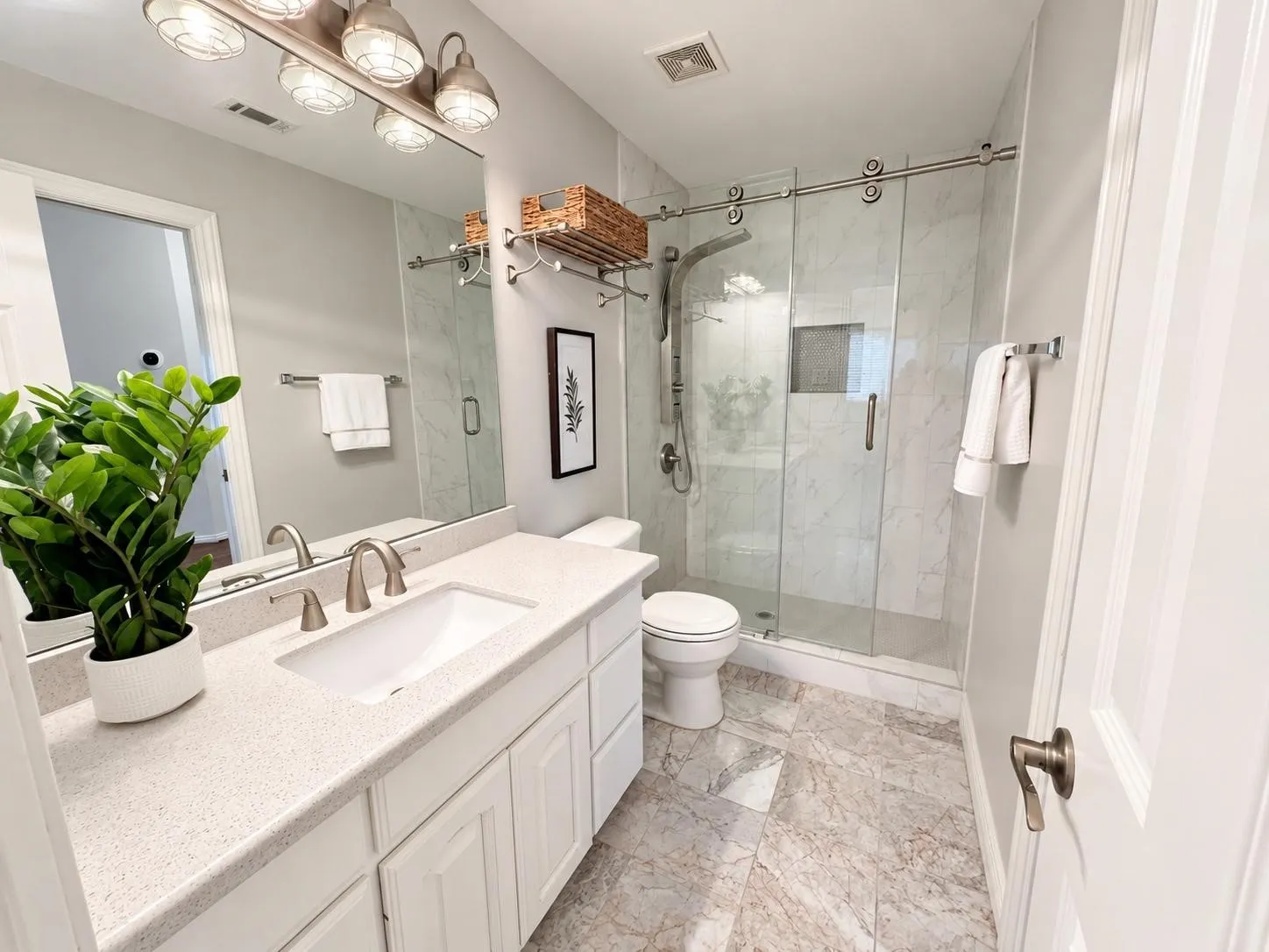 White vanity with a light speckled countertop, undermount sink, and brushed nickel faucet