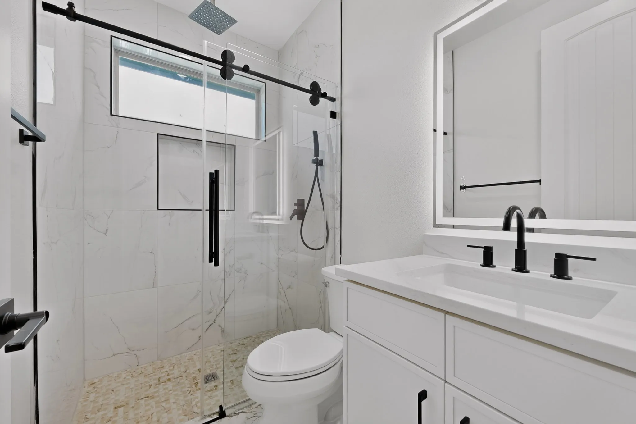 Shower with a sliding glass door, white tiled walls, and a pebble floor