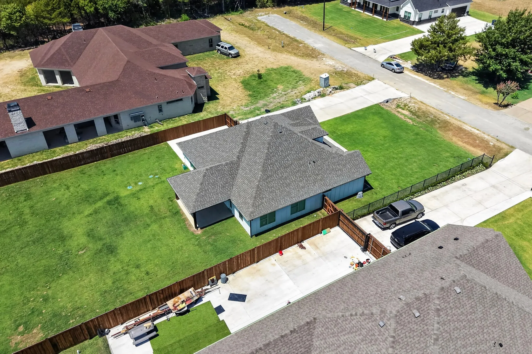 Expansive lot featuring a fenced backyard, concrete driveway, and covered patio