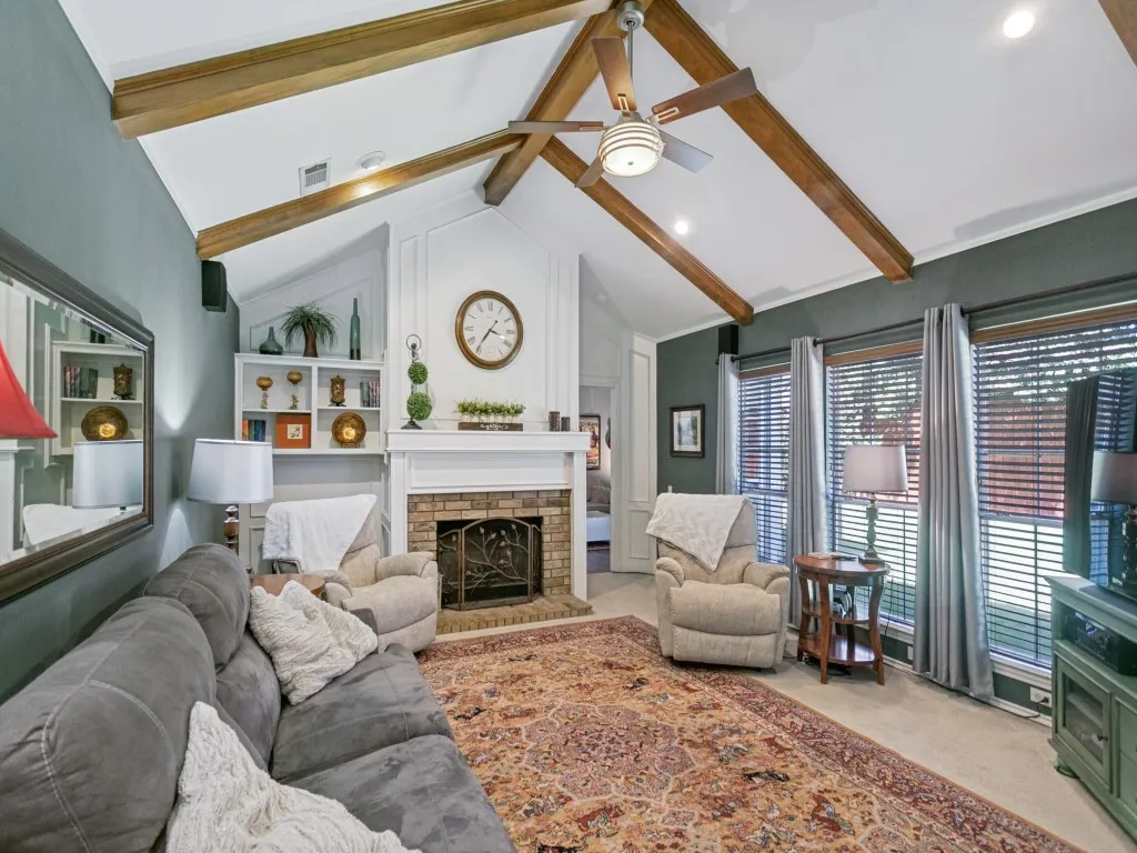 A second living area features vaulted ceiling with wood beams, a second fireplace, built-in shelving and backyard views.