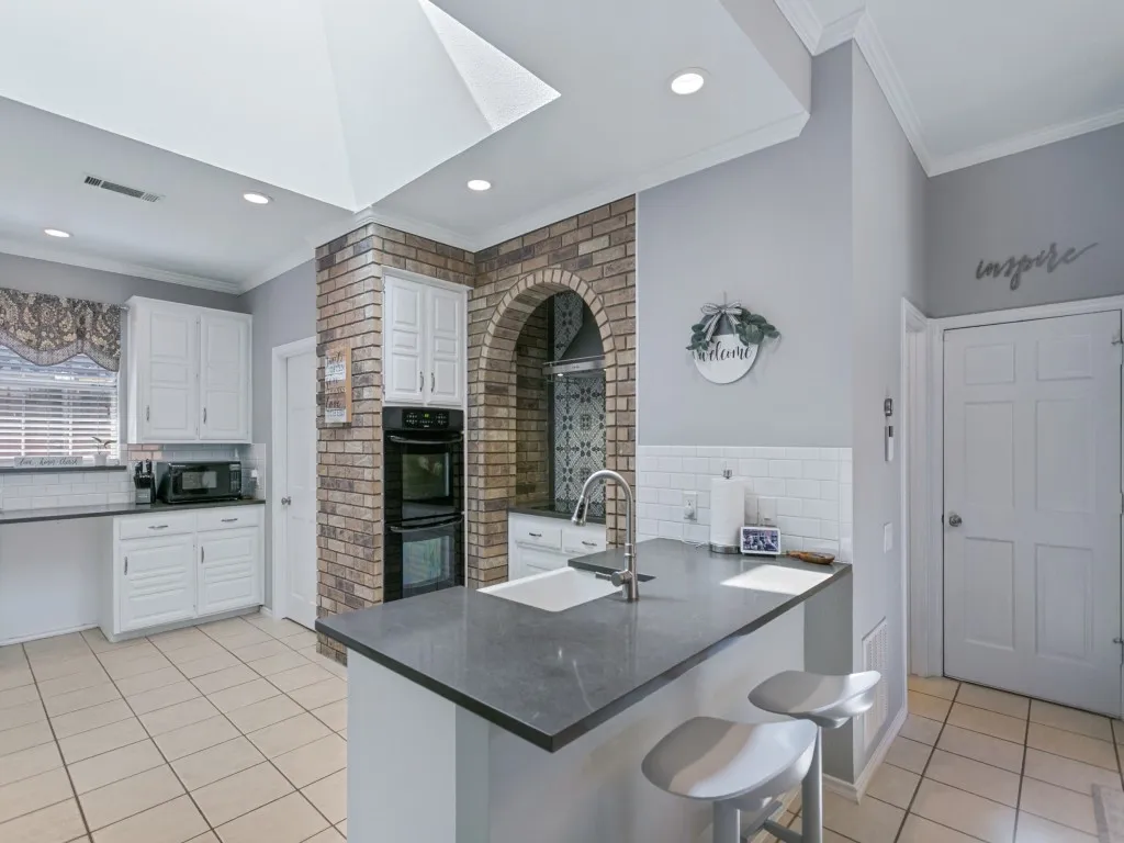 Kitchen featuring a skylight, recessed lighting and brick details.