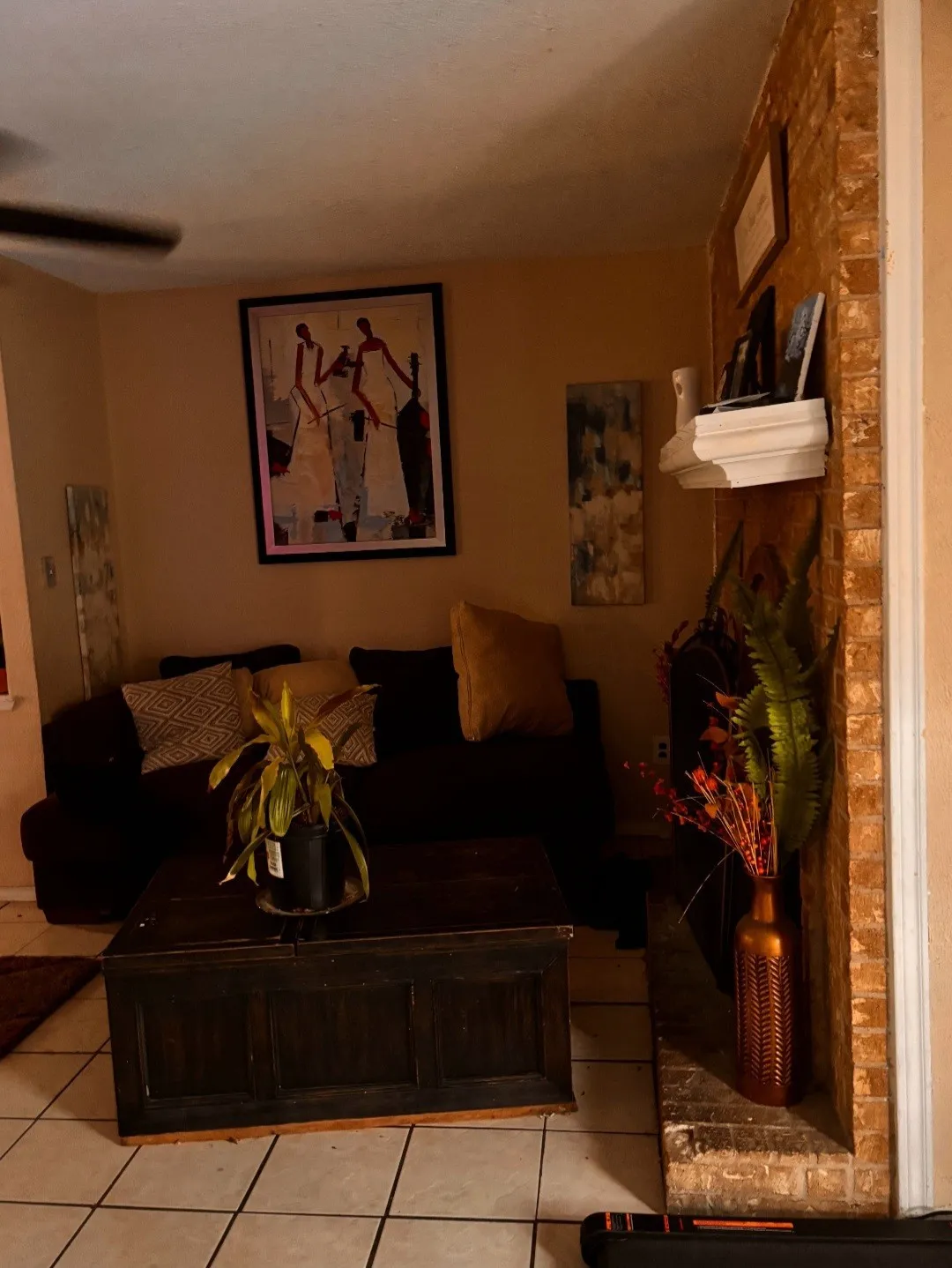 Tiled flooring, exposed brick wall, and a ceiling fan