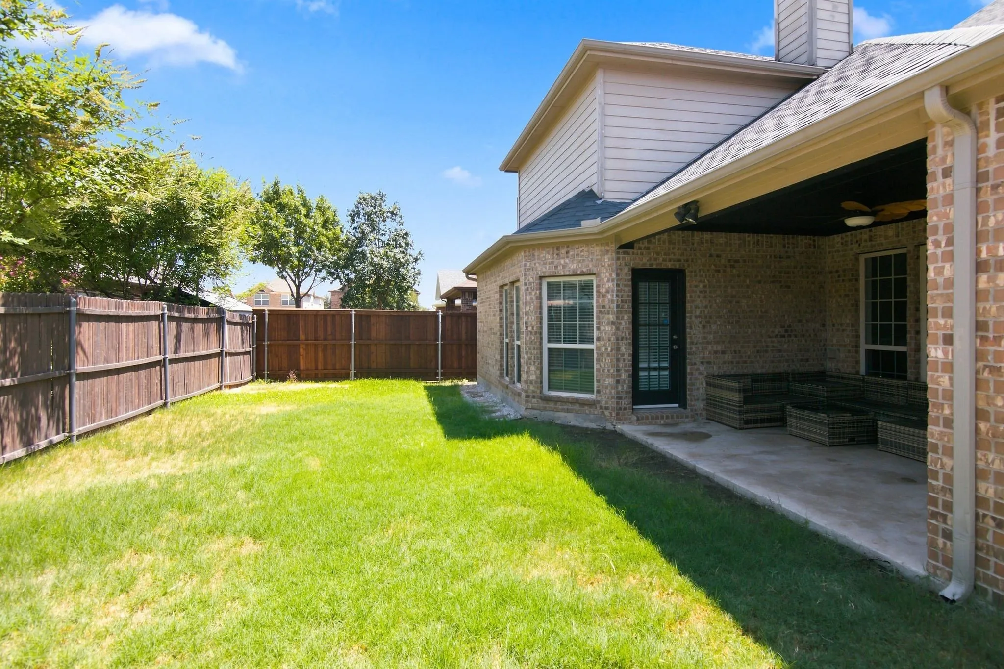 Covered patio with a ceiling fan and recessed lighting, brick exterior, multiple windows, and a privacy fence