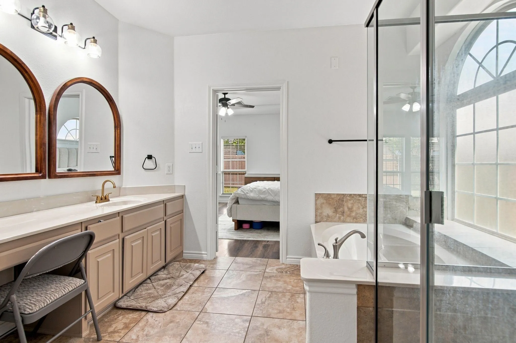 Dual vanity with single basin sinks, arched mirrors, and brass-tone fixtures