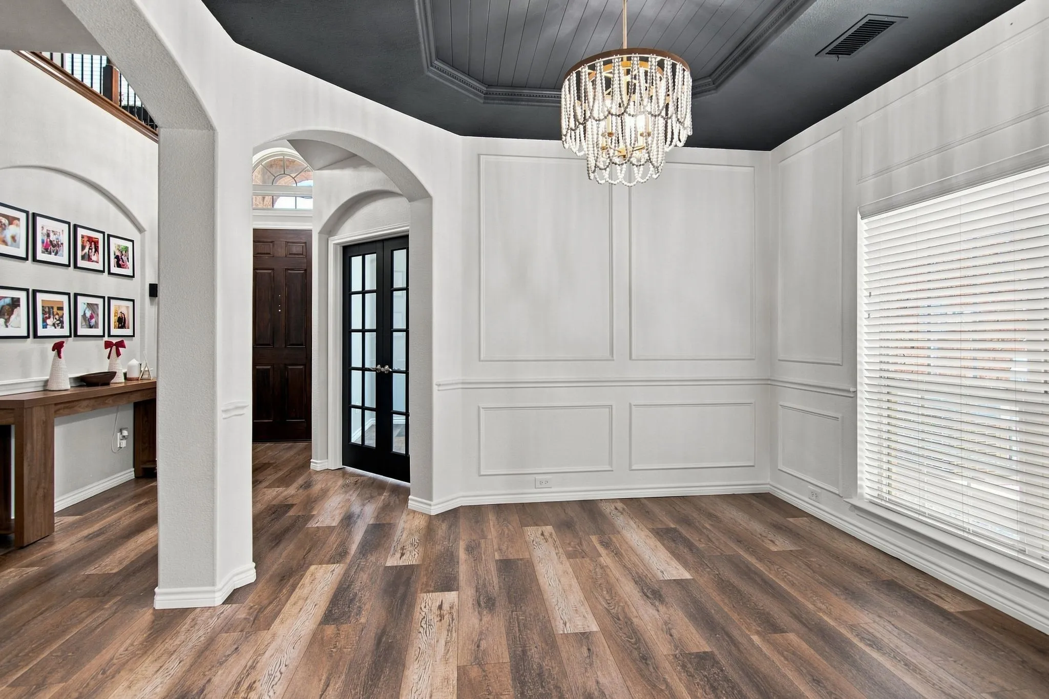 Wood-finish flooring throughout, with decorative wall paneling and an ornate chandelier