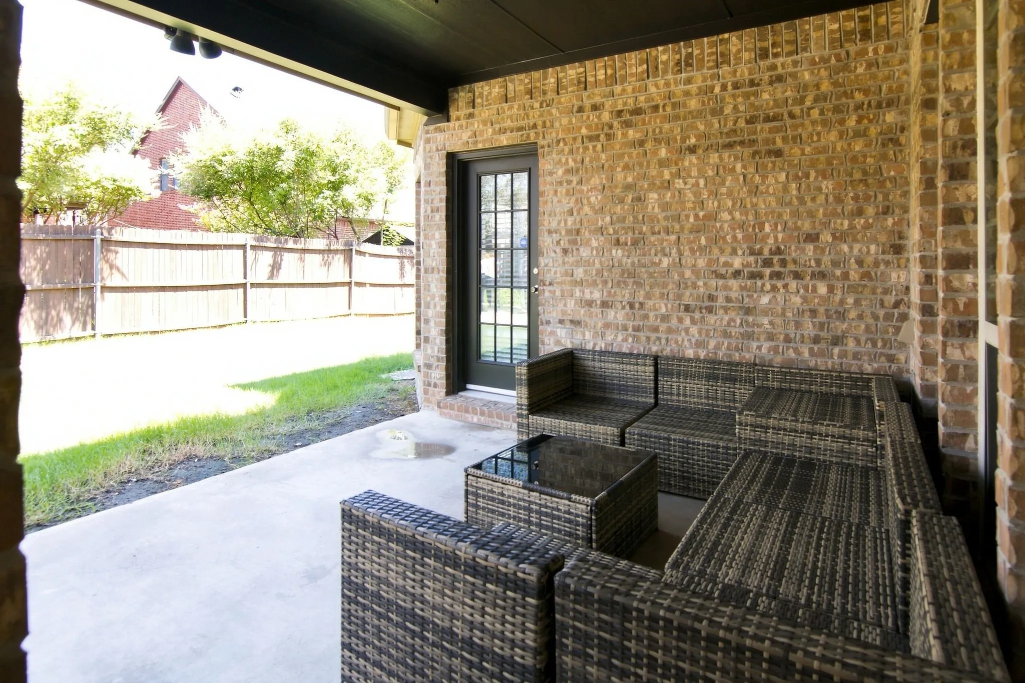 Covered patio featuring brick exterior walls and a glass-paneled door