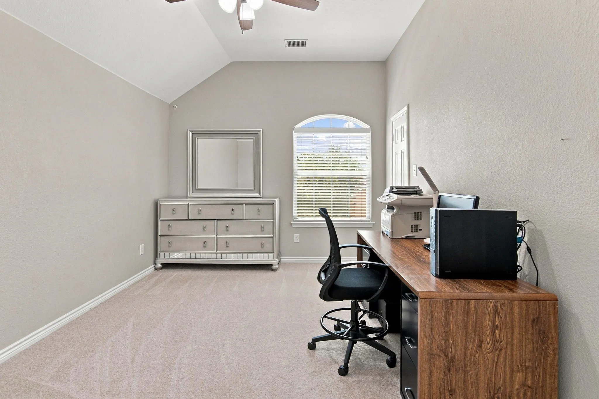 Vaulted ceiling with a ceiling fan, arched window with horizontal blinds, neutral-toned carpeting, and a two-panel interior door