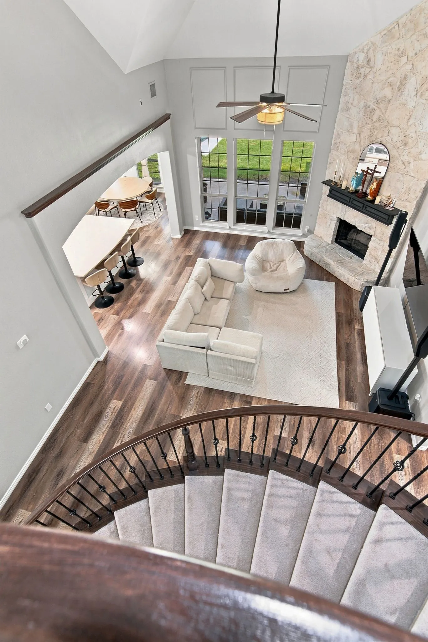 Vaulted ceiling living area with a stone-clad fireplace and large windows
