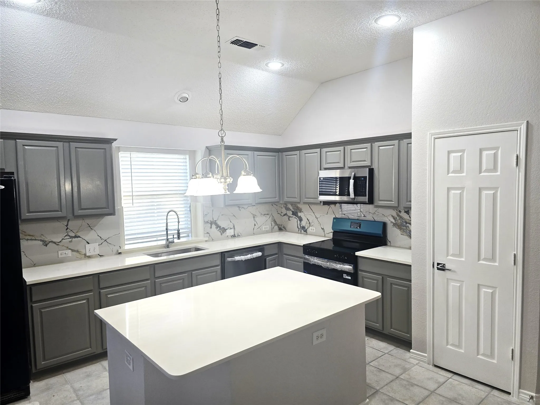 Kitchen featuring shaker-style cabinetry, a central island with a solid surface countertop, stainless steel appliances, a tile backsplash, and recessed lighting