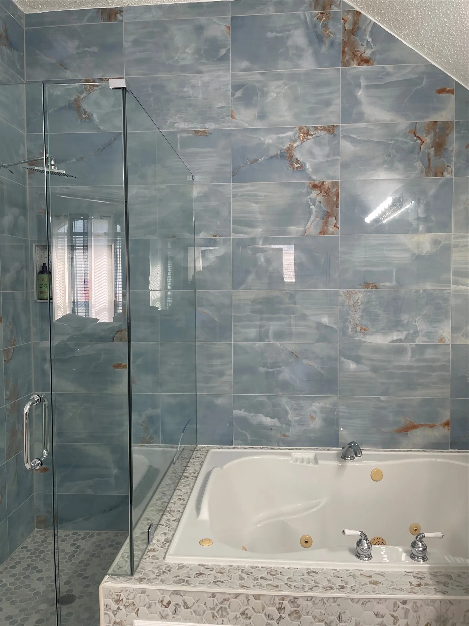 Shower with glass enclosure, rain showerhead, and blue veined tile surround