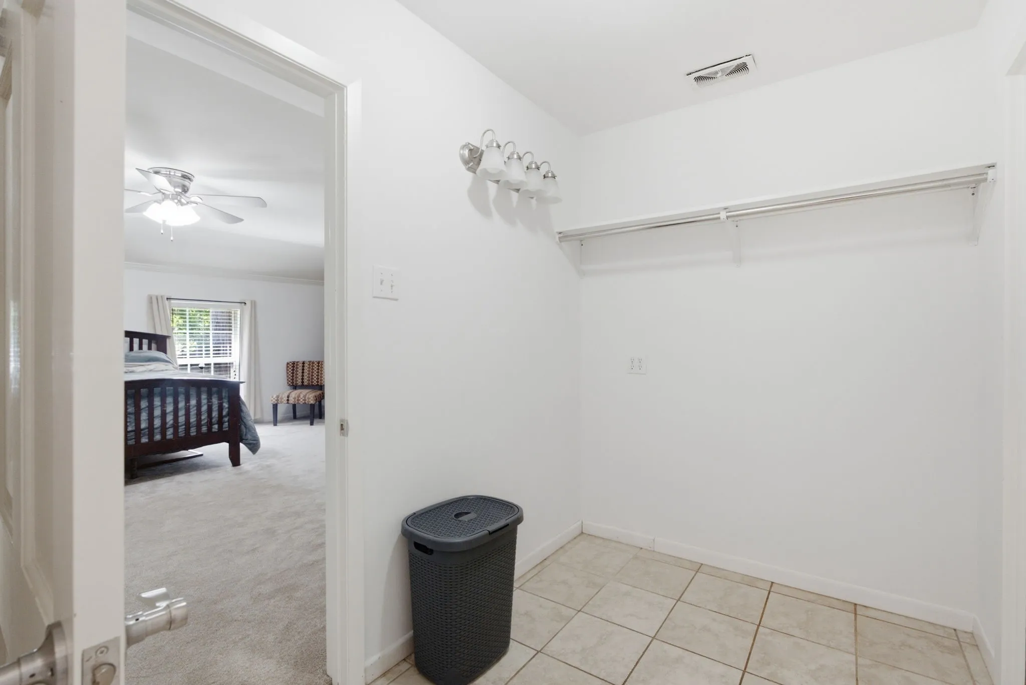 Walk-in closet with tile flooring, shelving, and wall-mounted lighting