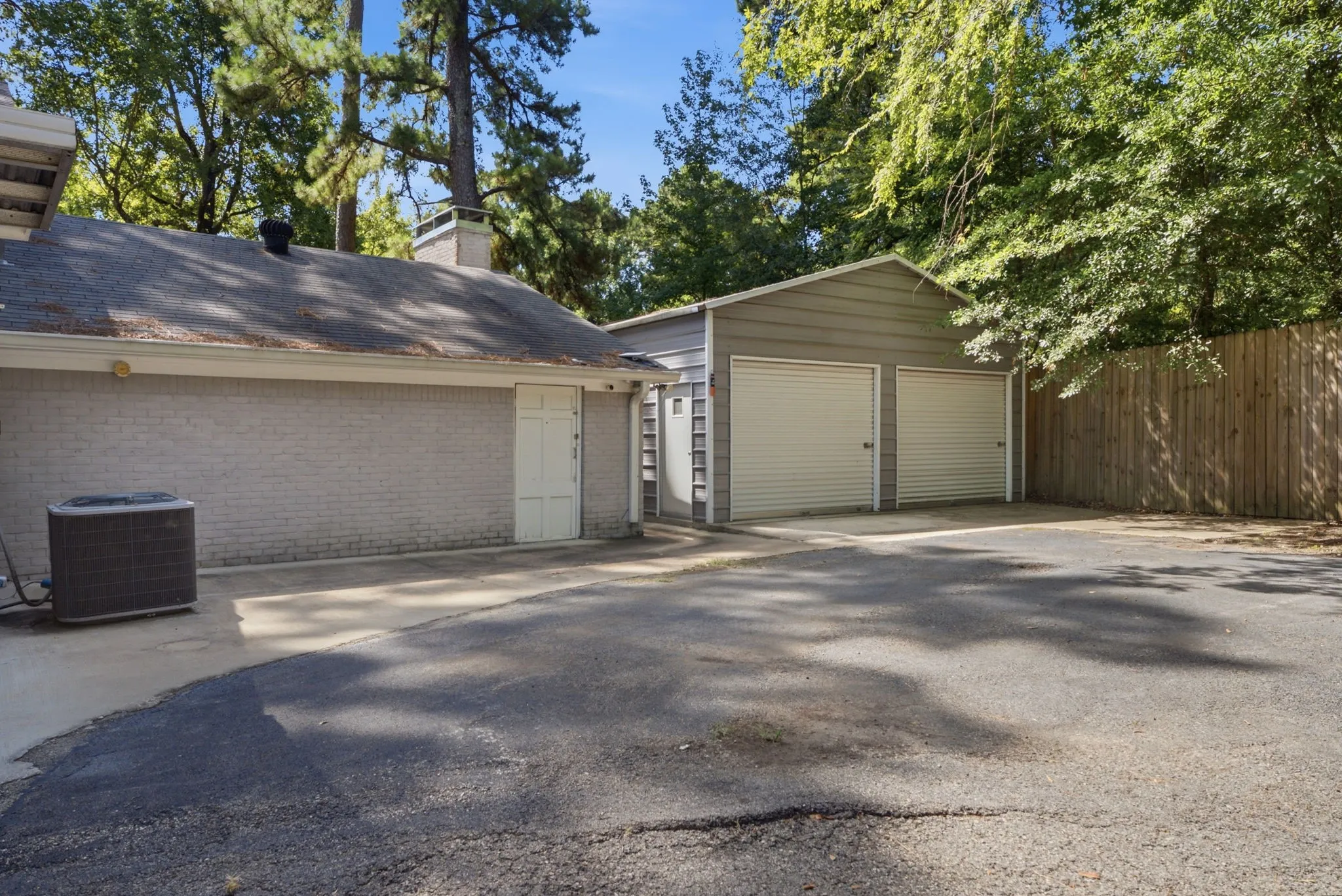 Paved driveway accessing a two-car garage with roll-up doors, and an additional single-car garage