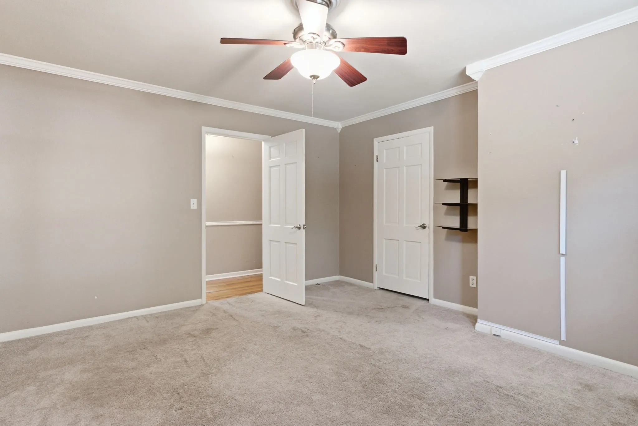 Ceiling fan with light fixture, crown molding, white paneled doors, carpeted flooring, built-in shelving