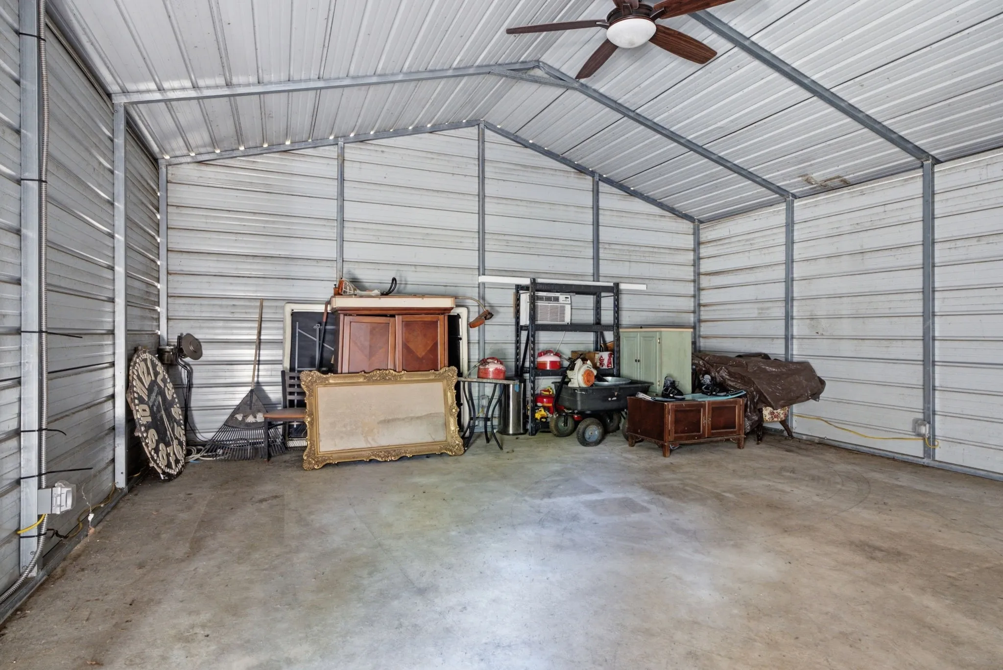 Metal construction carport with a concrete floor and a ceiling fan