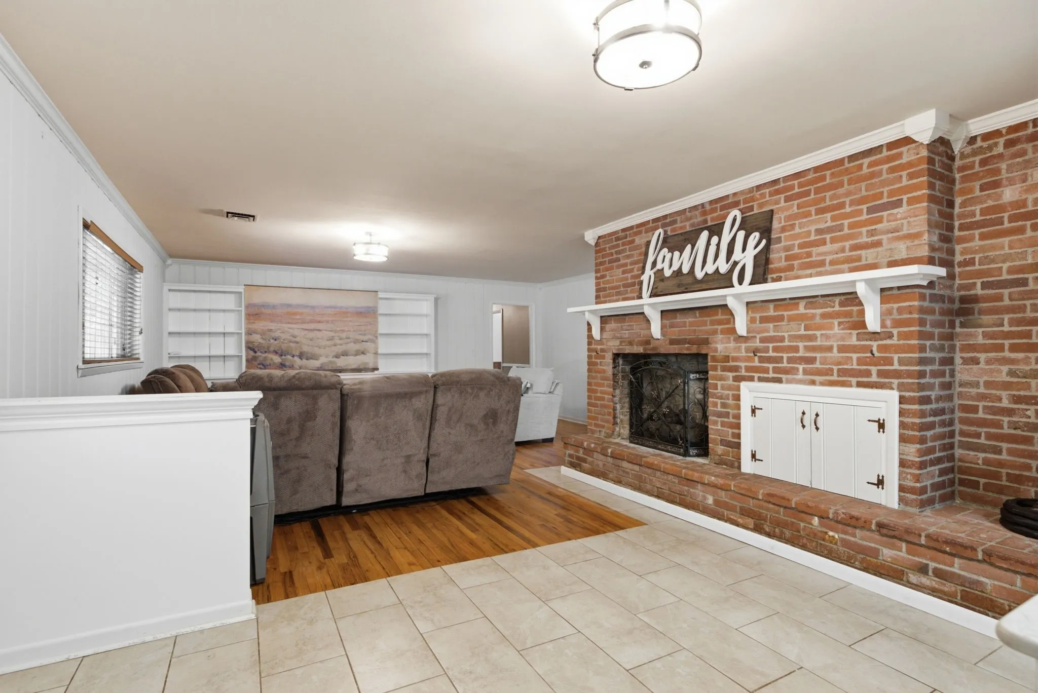Brick fireplace with hearth, built-in storage, wood-finish flooring, recessed lighting, and integrated shelving