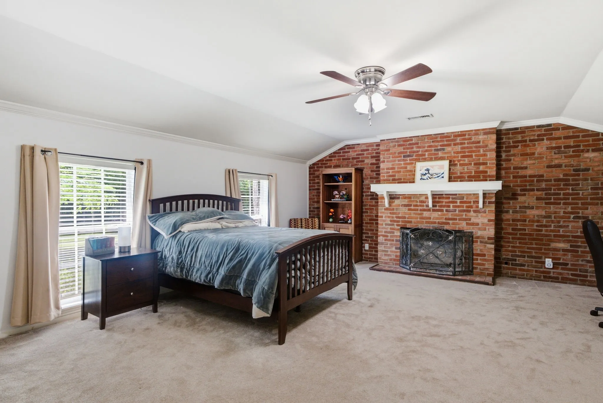 Brick accent wall with a fireplace, crown molding, and a ceiling fan