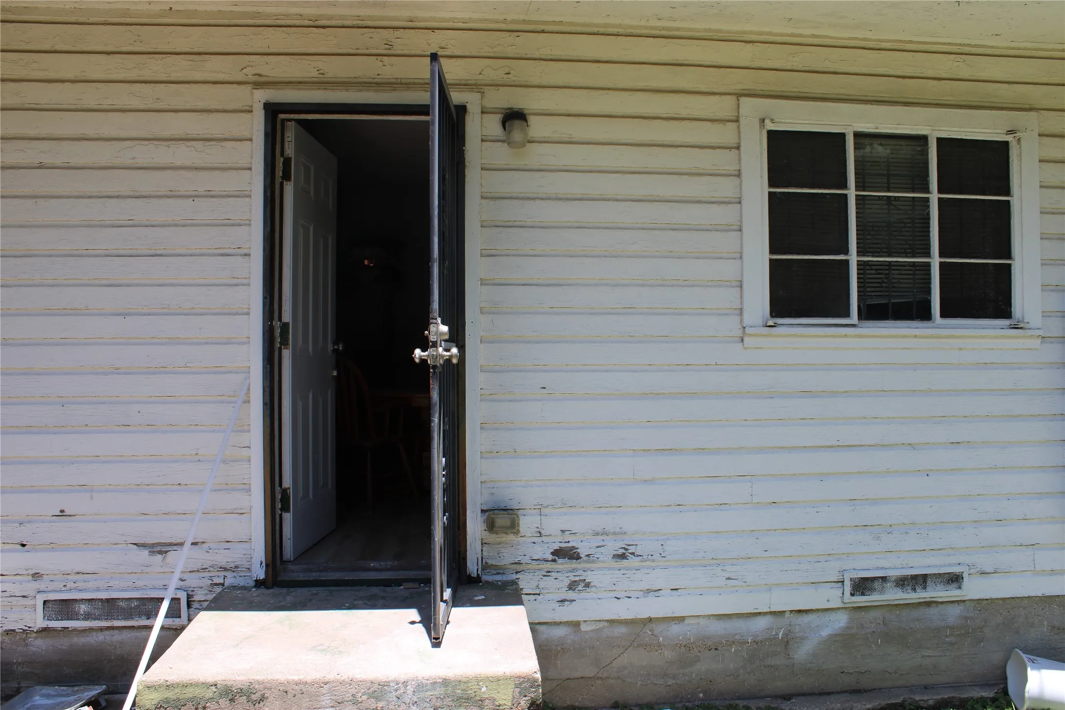 Exterior featuring horizontal siding, a multi-pane window, and a concrete entry step