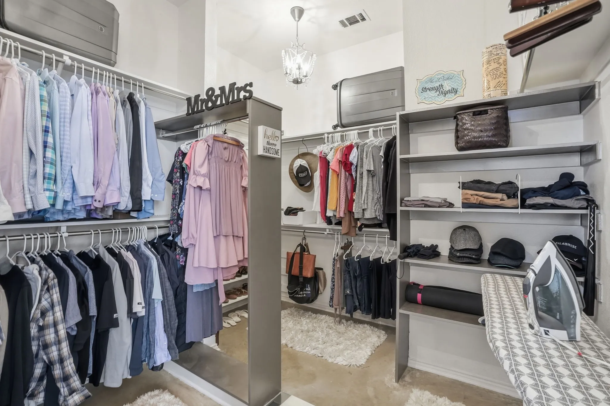 Built-in custom shelving, multiple clothing rods, overhead storage, and chandelier in this incredible closet