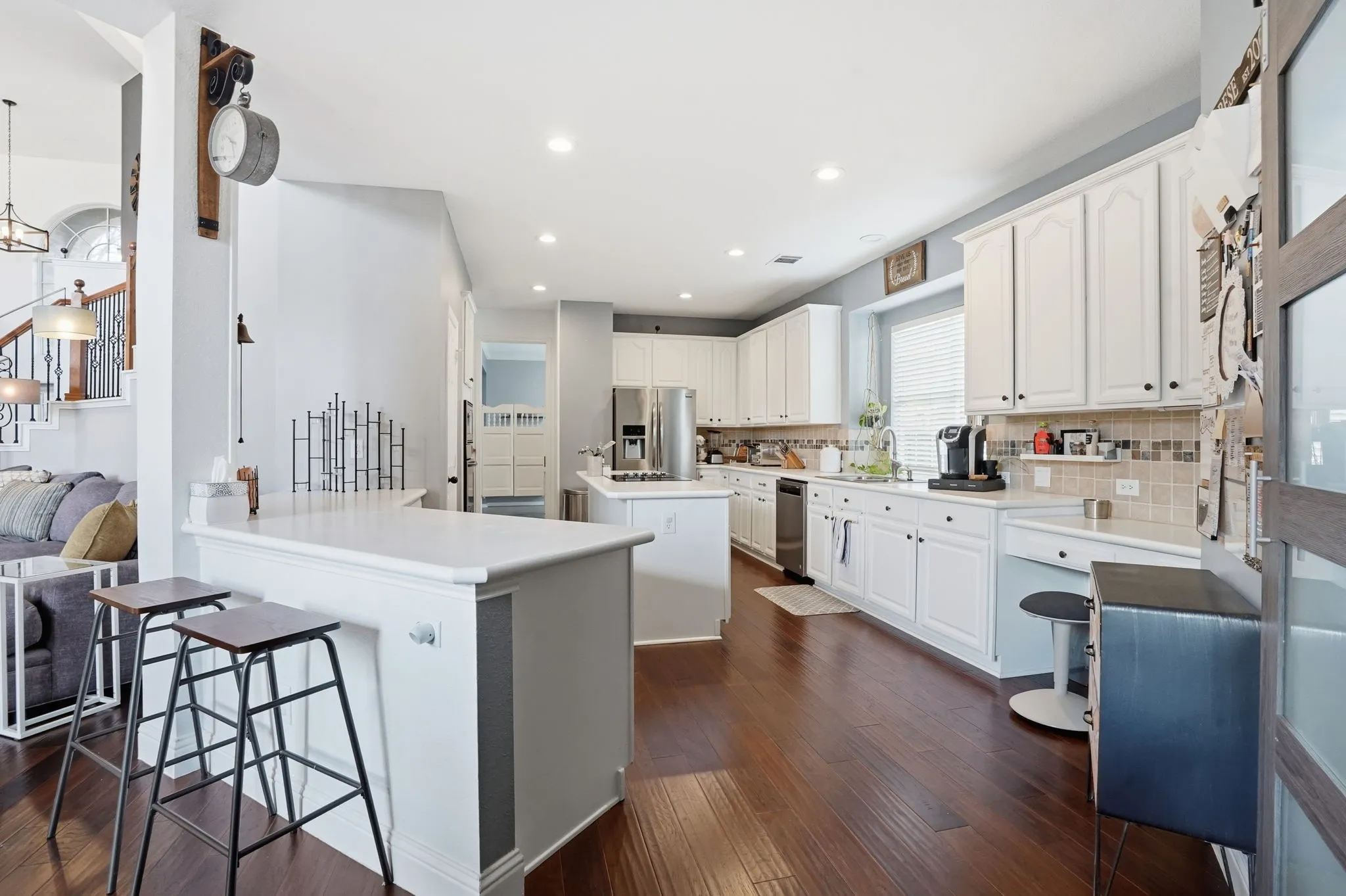 Open-concept kitchen with white cabinetry, stainless steel appliances, and wood flooring