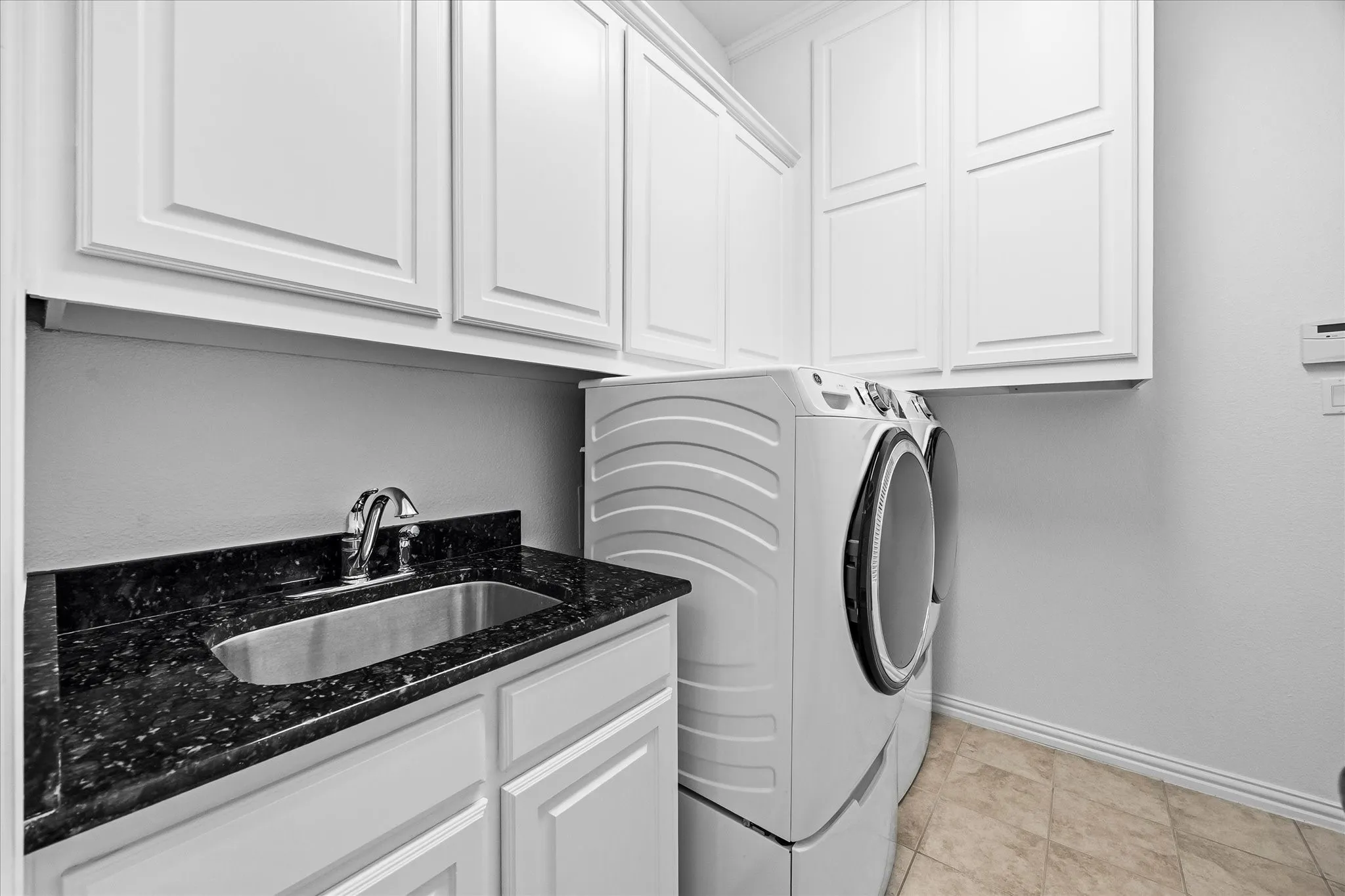 The spacious laundry room has a sink, granite counter, storage cabinets, mud bench and LAUNDRY CHUTE!