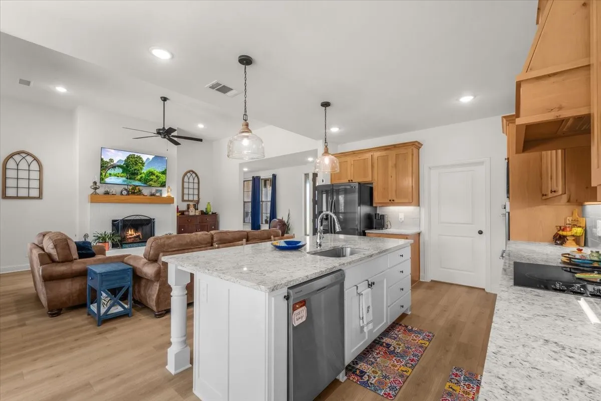 Kitchen: Large center island with integrated sink and dishwasher anchors the kitchen while maintaining an open connection to the living room and fireplace.