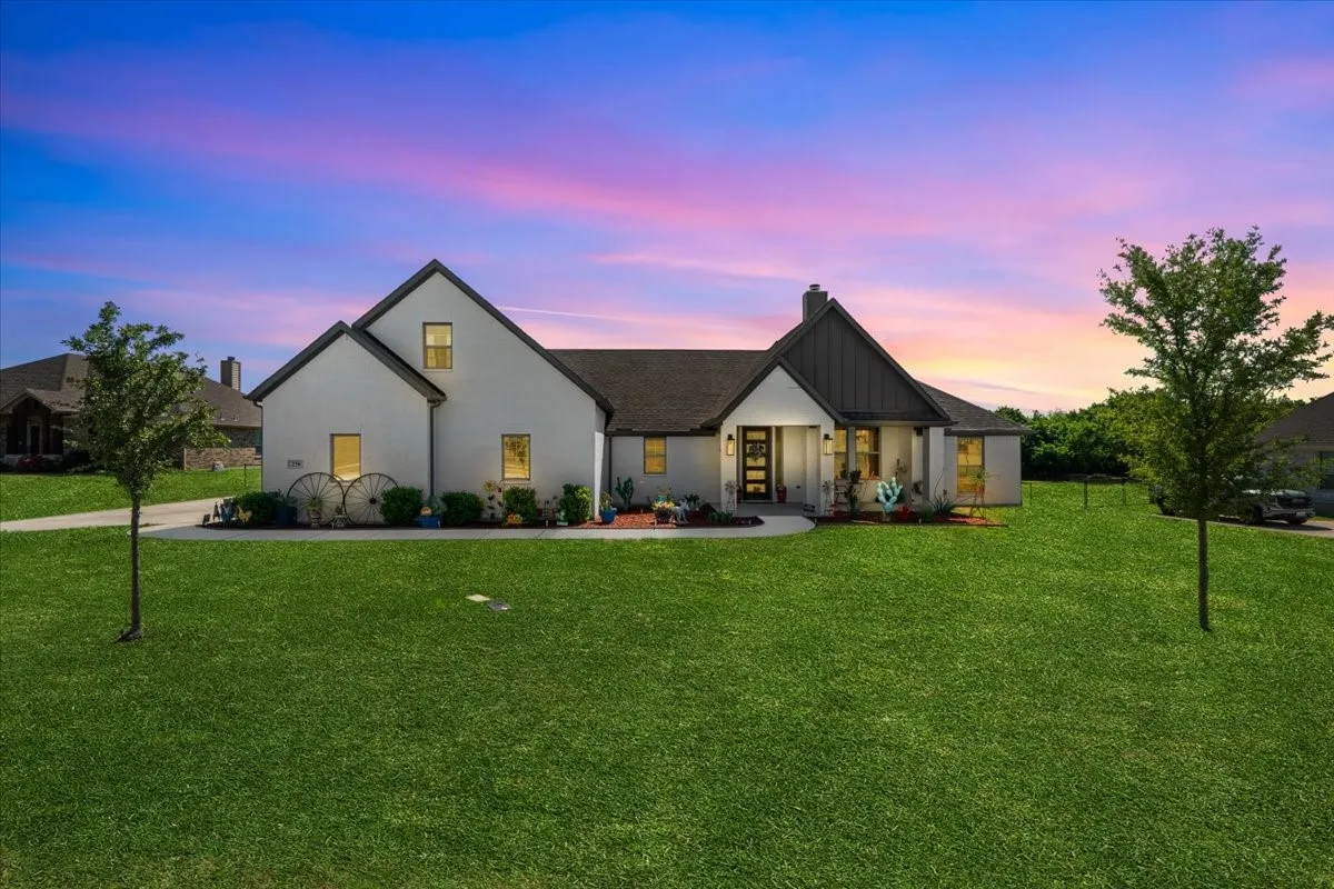 Exterior: Wide front view showcases a white-painted exterior, contrasting dark gable accents, covered entry, and expansive lawn. AI- green grass