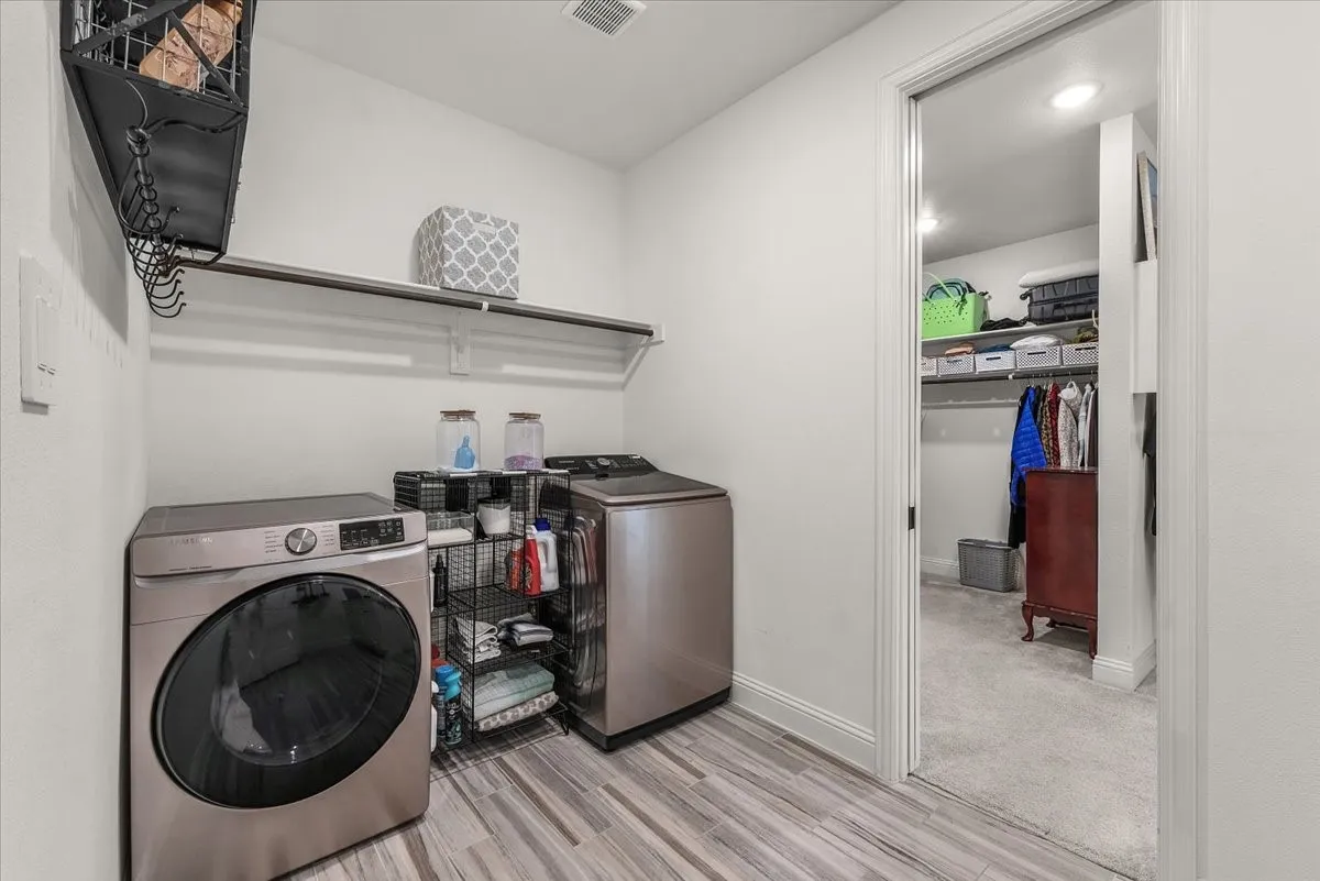 Laundry Room: Dedicated laundry space offers overhead hanging storage, durable tile flooring, and direct access to the adjoining walk-in closet.