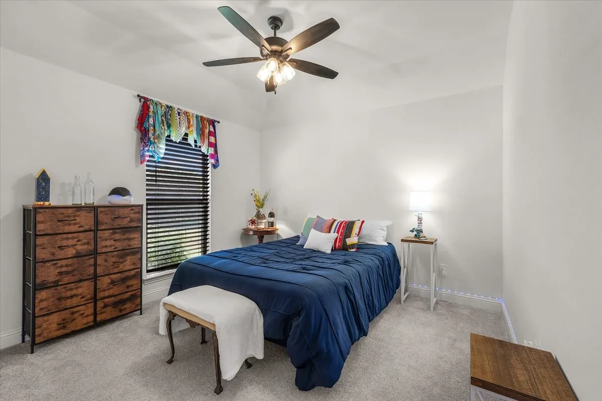 Bedroom: Carpeted bedroom features neutral finishes, a ceiling fan, and a large window providing natural light.