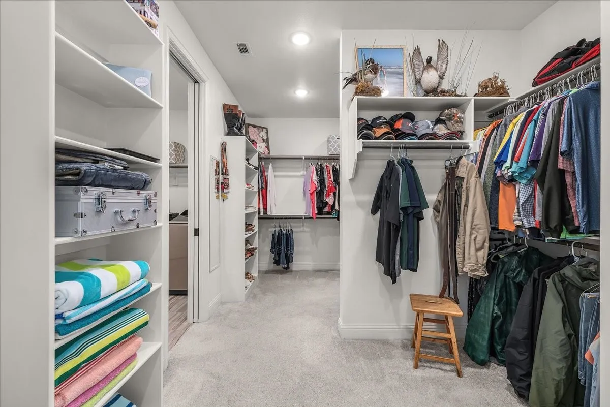 Walk-In Closet: Generous closet layout provides multiple hanging sections, built-in shelving, and dedicated storage areas beneath recessed lighting.