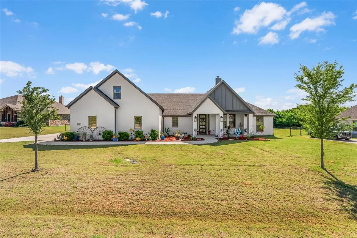 Aerial Exterior: Elevated front view showcases the home’s gabled architecture, covered entry, landscaped frontage, driveway, and surrounding green space.