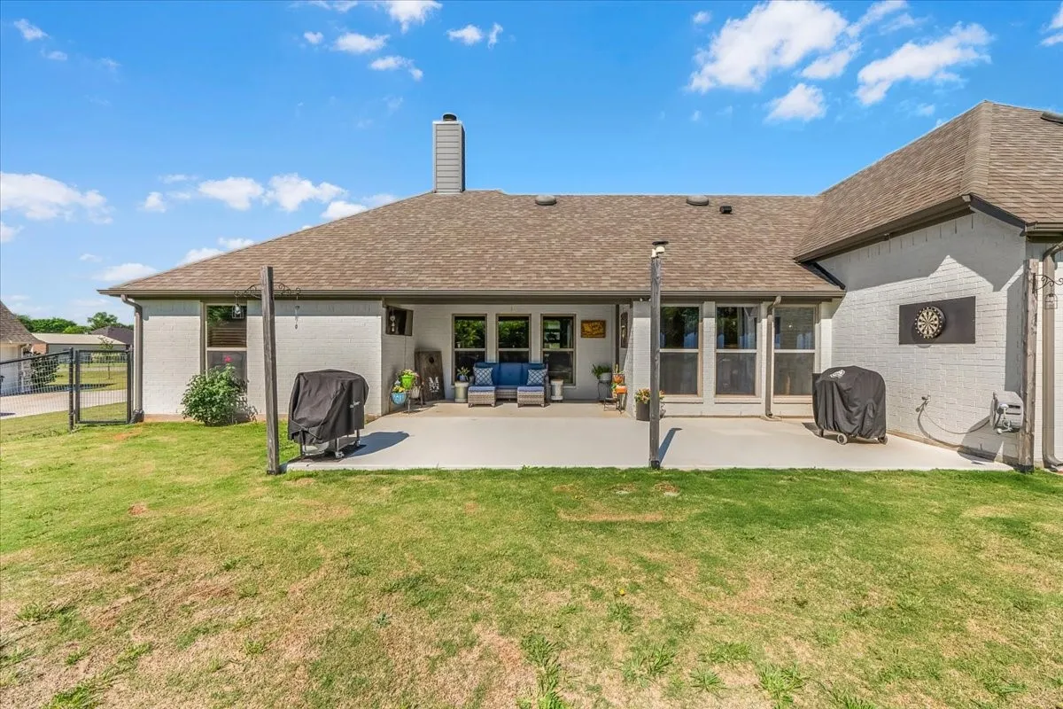 Back Patio: Spacious concrete patio extends across the rear of the home with multiple access points to the interior and an open view of the backyard.