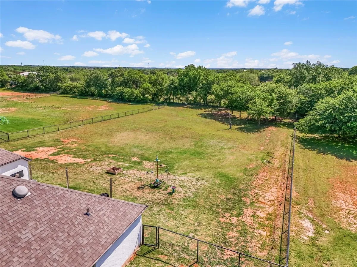 Aerial view showcasing the approximately 1-acre fenced property with a spacious backyard and plenty of room for a future shop and pool.
