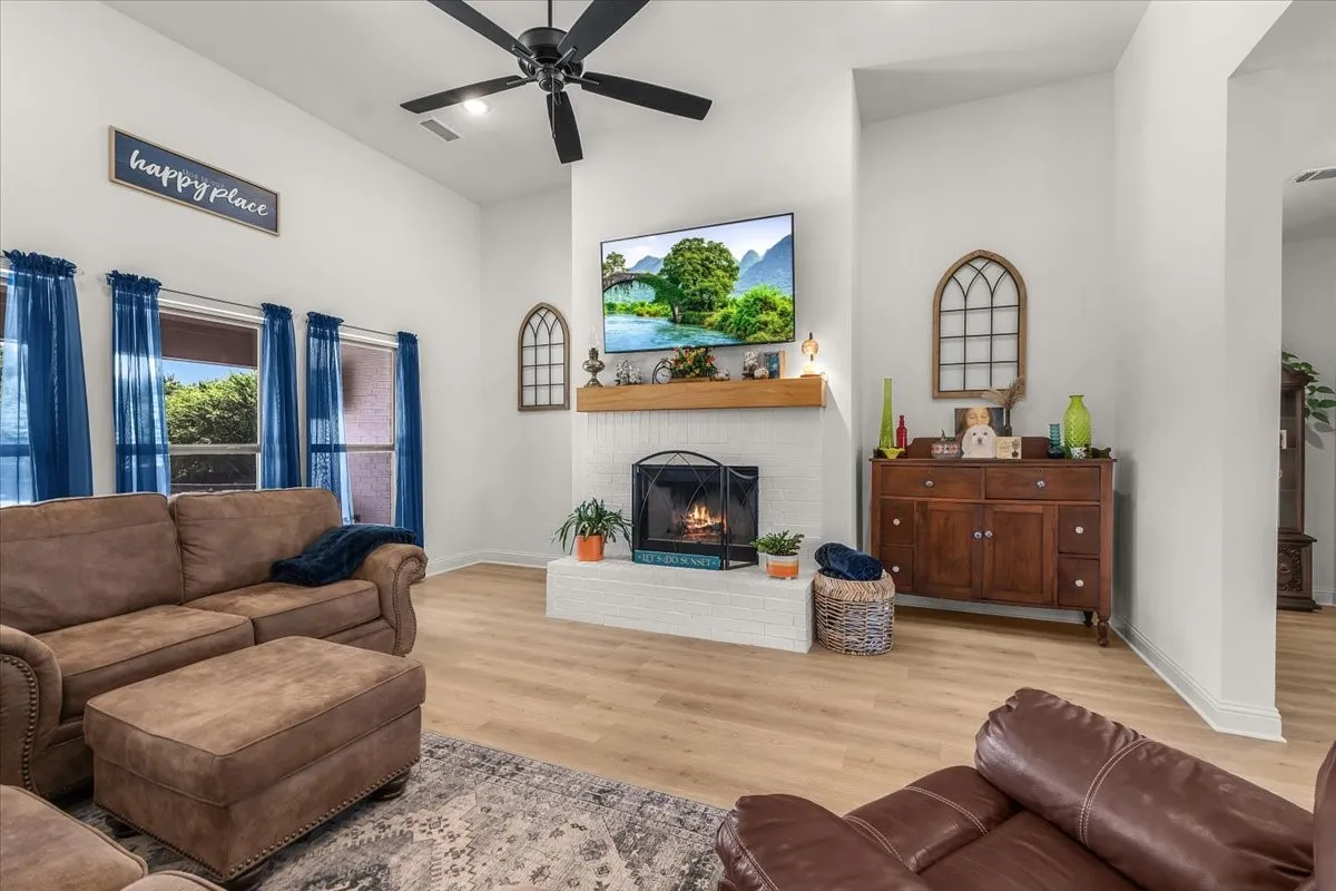 Living Room: Fireplace creates a focal point beneath the vaulted ceiling, while tall windows and wood-look flooring add to the room’s open feel.