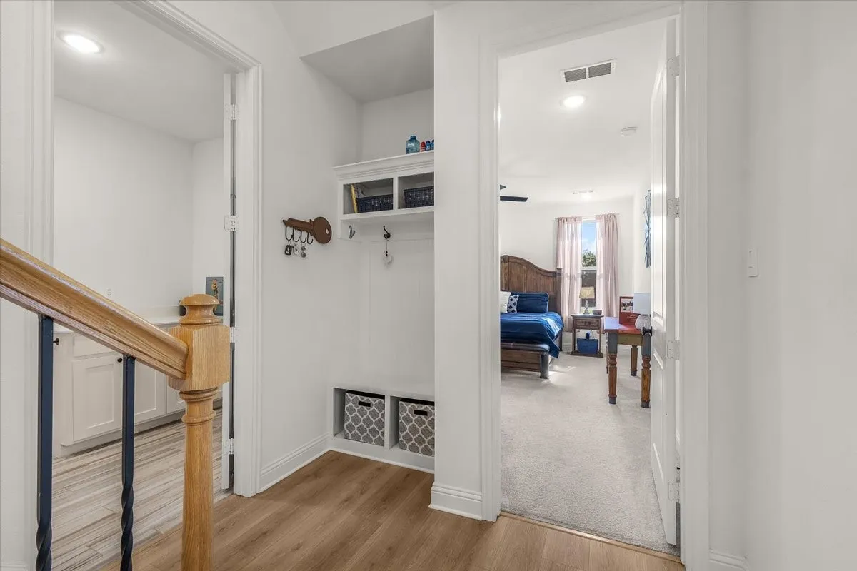Hallway: Interior hall includes wood-look flooring, built-in storage with hooks and cubbies, and convenient access to adjoining rooms.