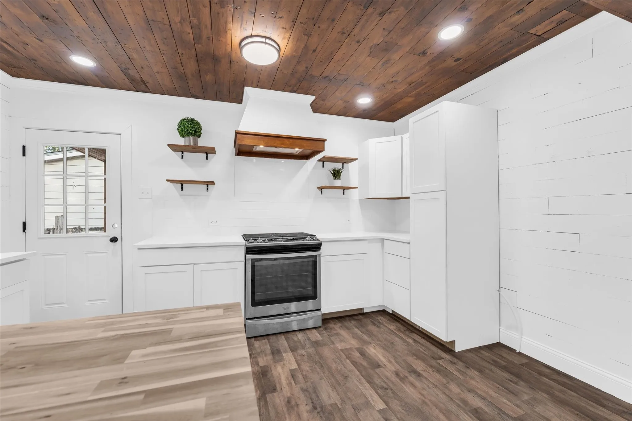 Kitchen featuring wood-finish flooring, white cabinetry, stainless steel range, white countertops, and a paneled wood ceiling