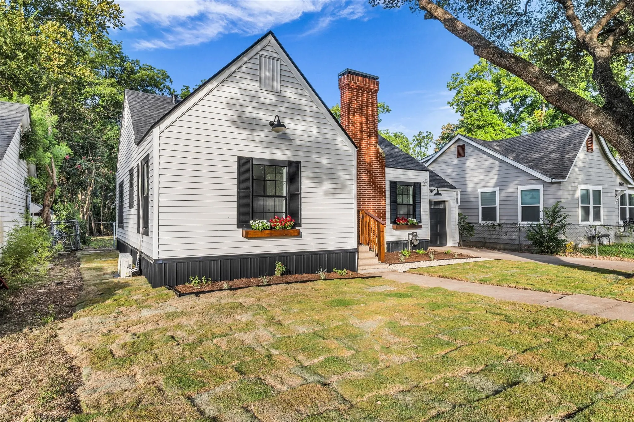 White siding exterior with black shutters, brick chimney, and a front walkway
