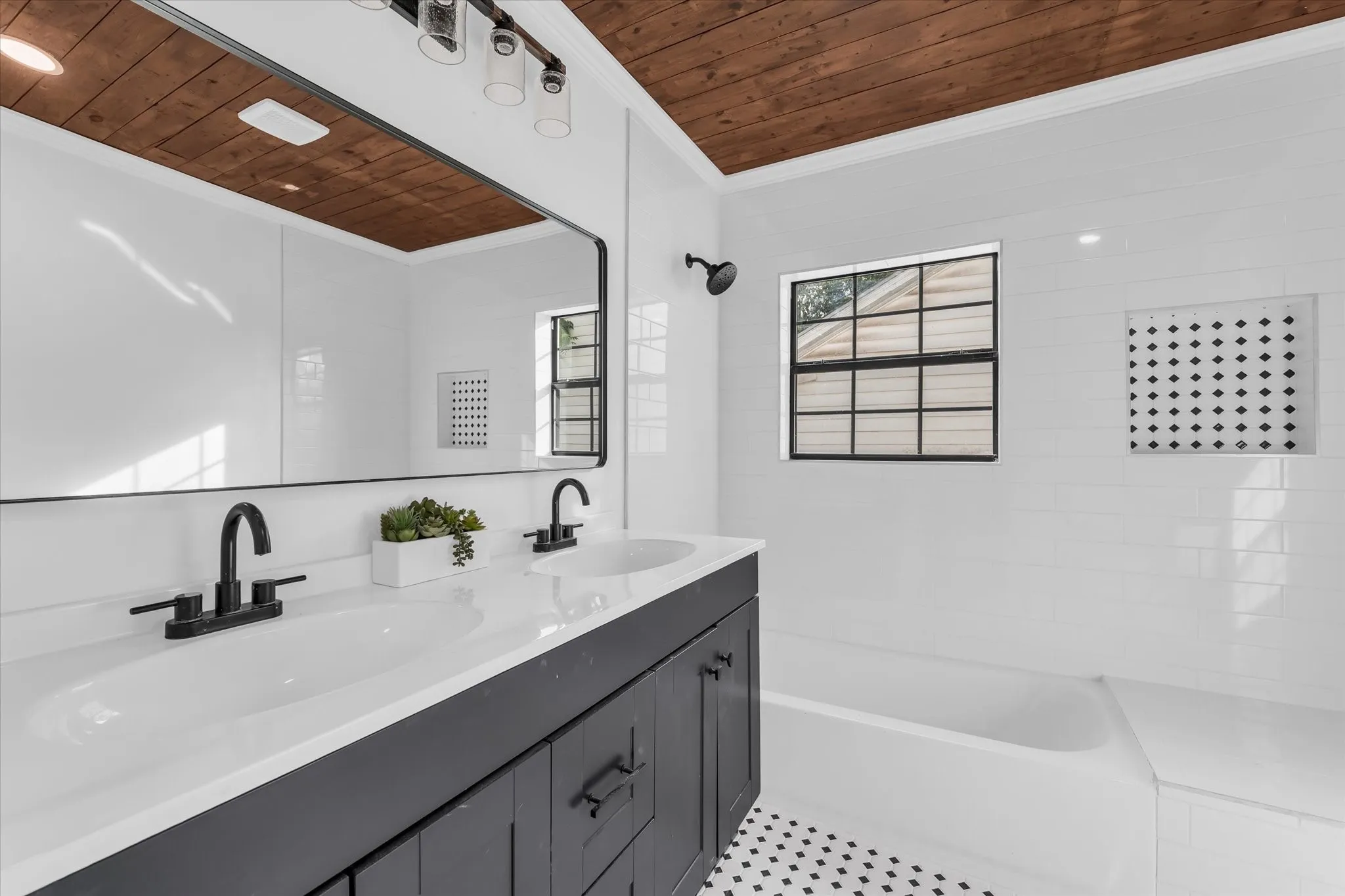 Dual vanity with white countertop, matte black fixtures, and wood-paneled ceiling