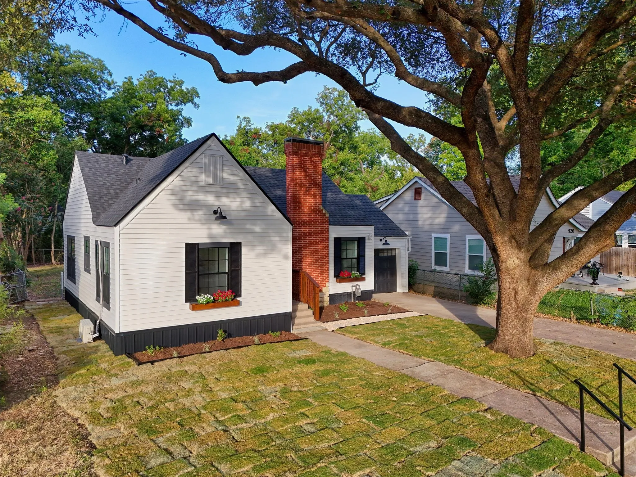 White horizontal siding with a dark vertical accent, brick chimney, black shutters, and a window box