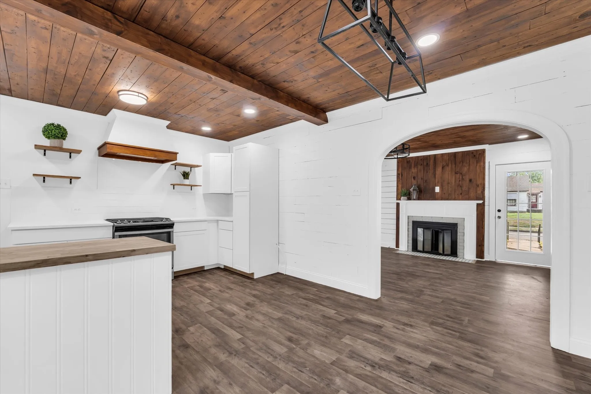 Wood-finish plank ceiling with exposed beams, recessed lighting, and a contemporary chandelier