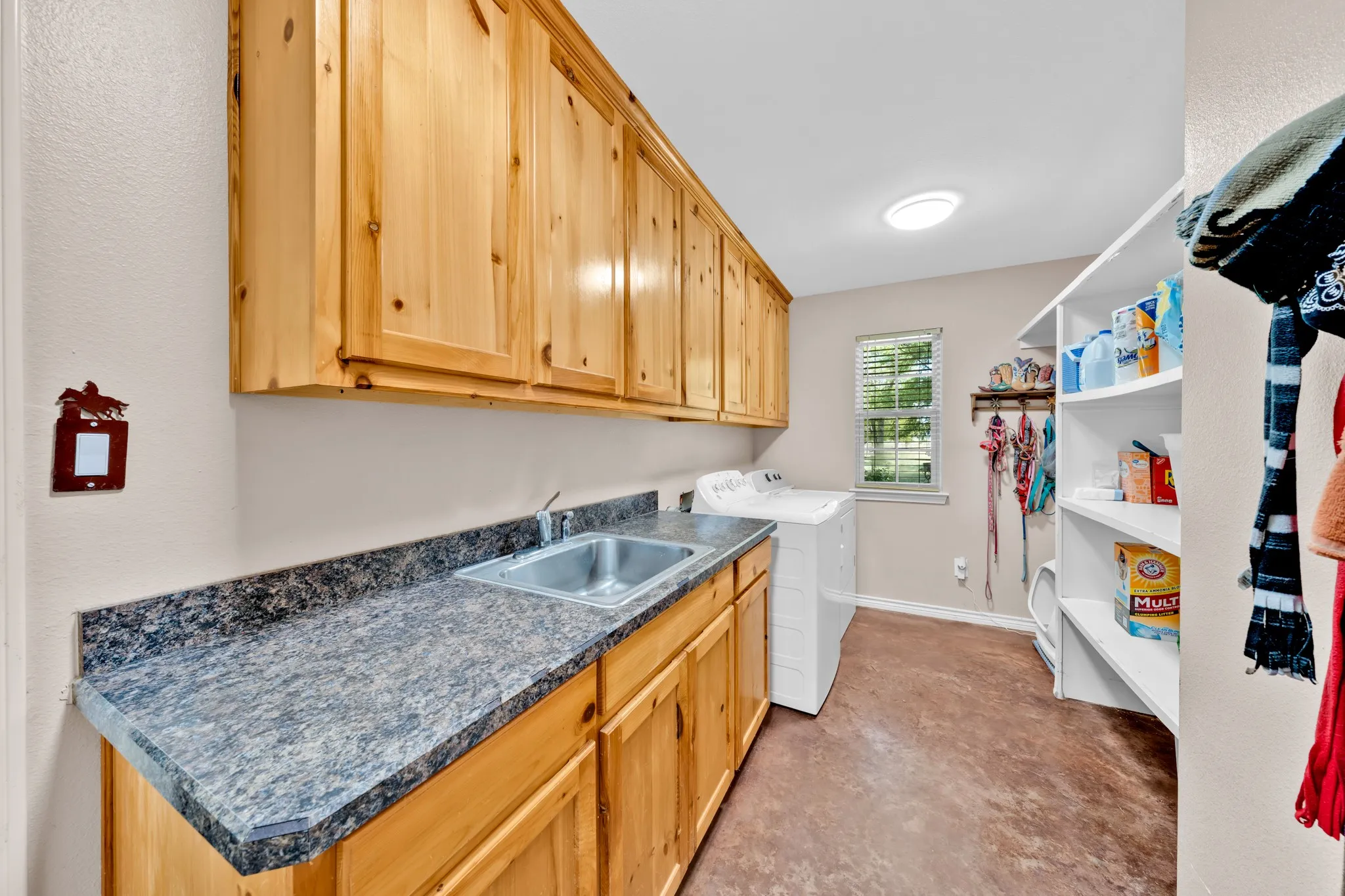 Laundry area with wood-finish cabinetry, a utility sink, and stone-finish countertops