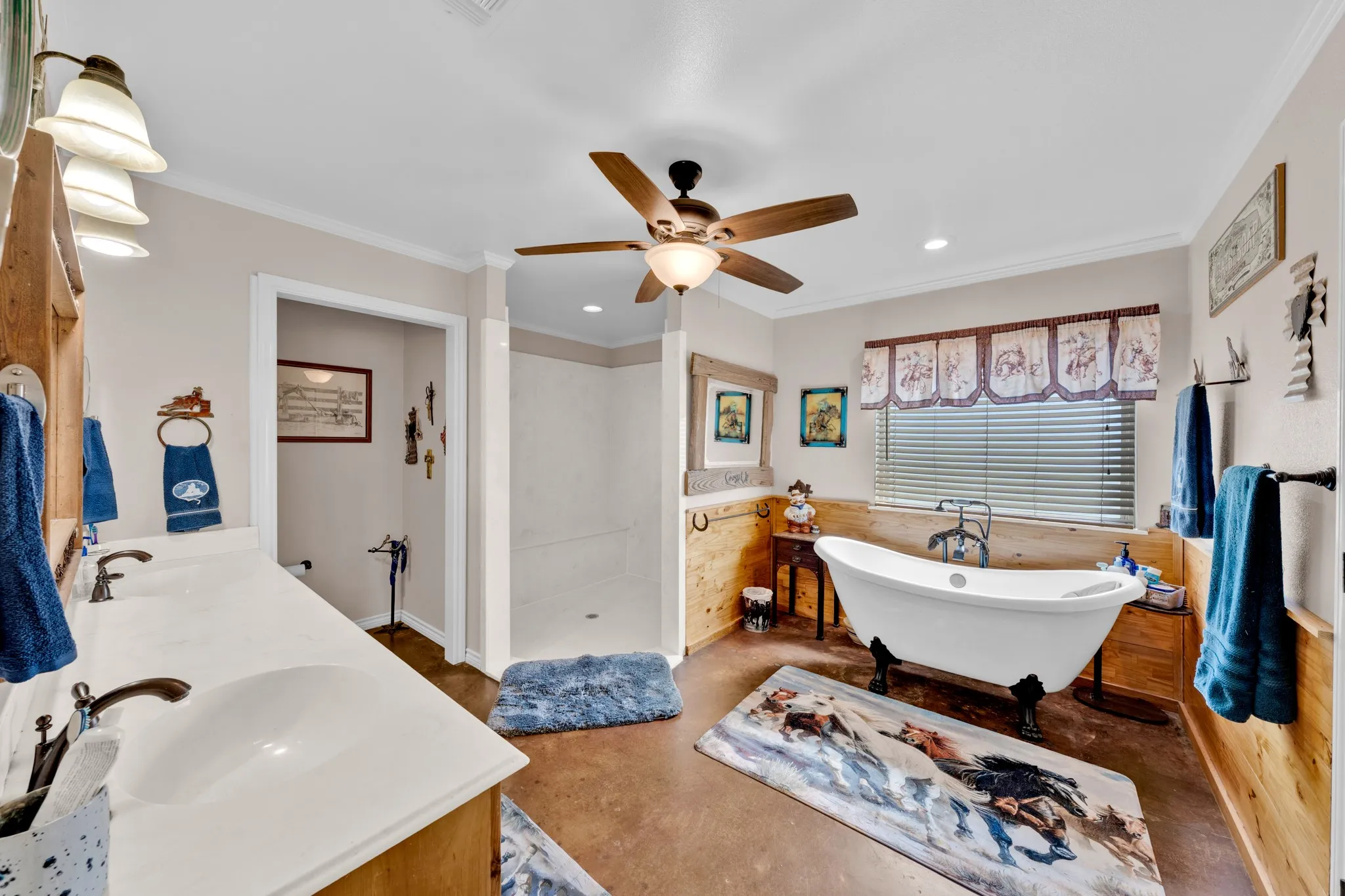 Spacious bathroom featuring a dual vanity with white countertops, a walk-in shower, a freestanding clawfoot tub, and a ceiling fan