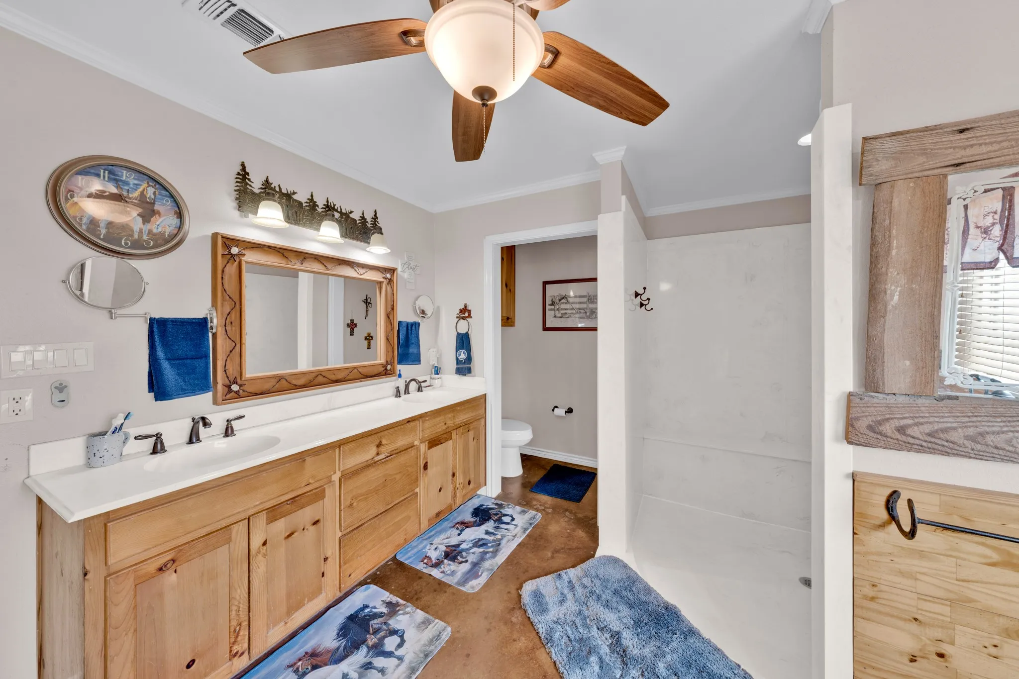 Dual vanity with integrated sinks, wood-finish cabinetry, and a ceiling fan with light fixture
