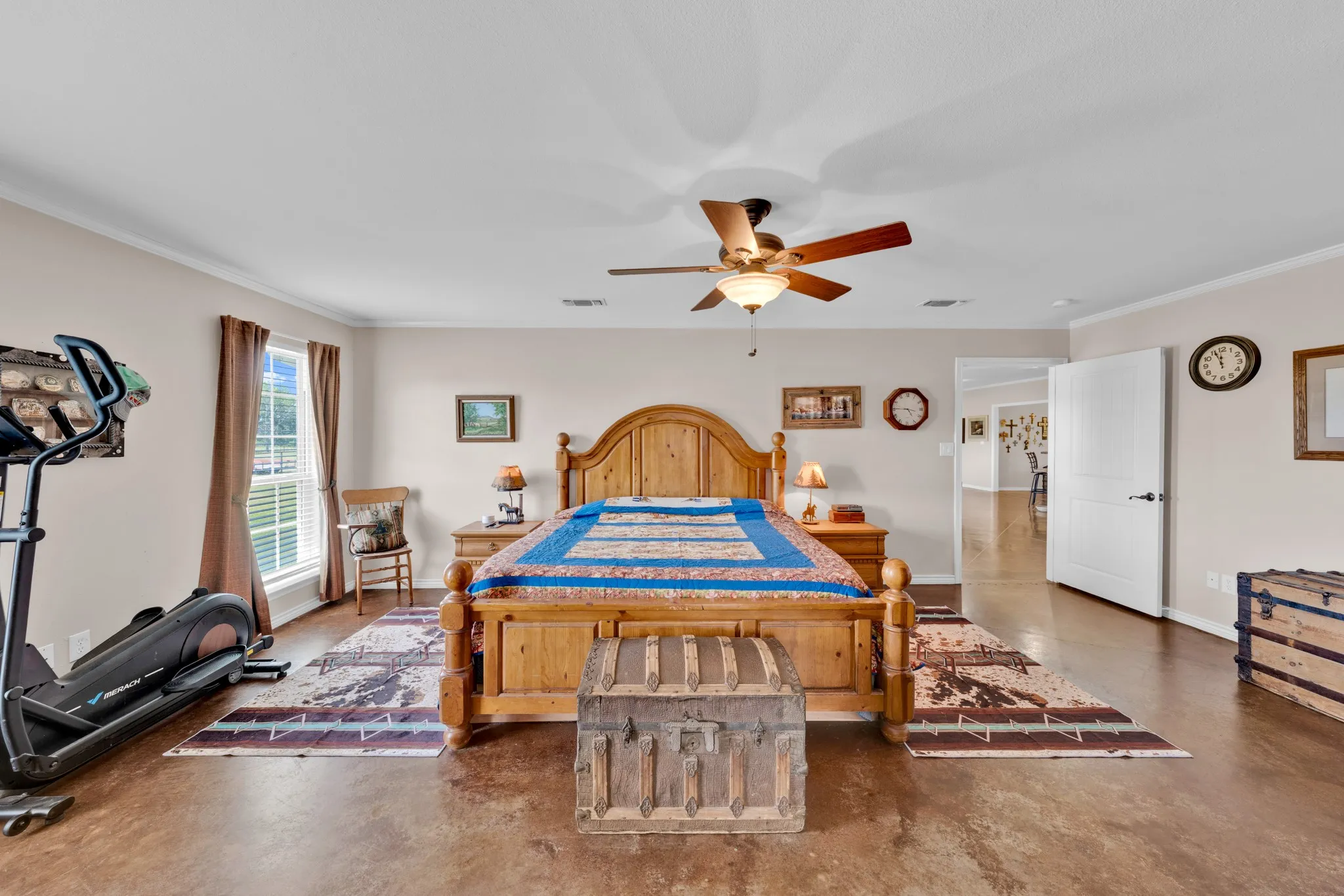 Spacious room featuring wood-finish flooring, a ceiling fan, and crown molding