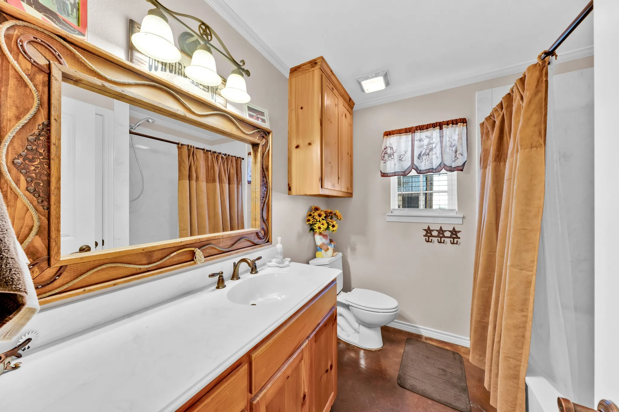 Wooden vanity with integrated sink, wooden framed mirror, and a wall-mounted light fixture