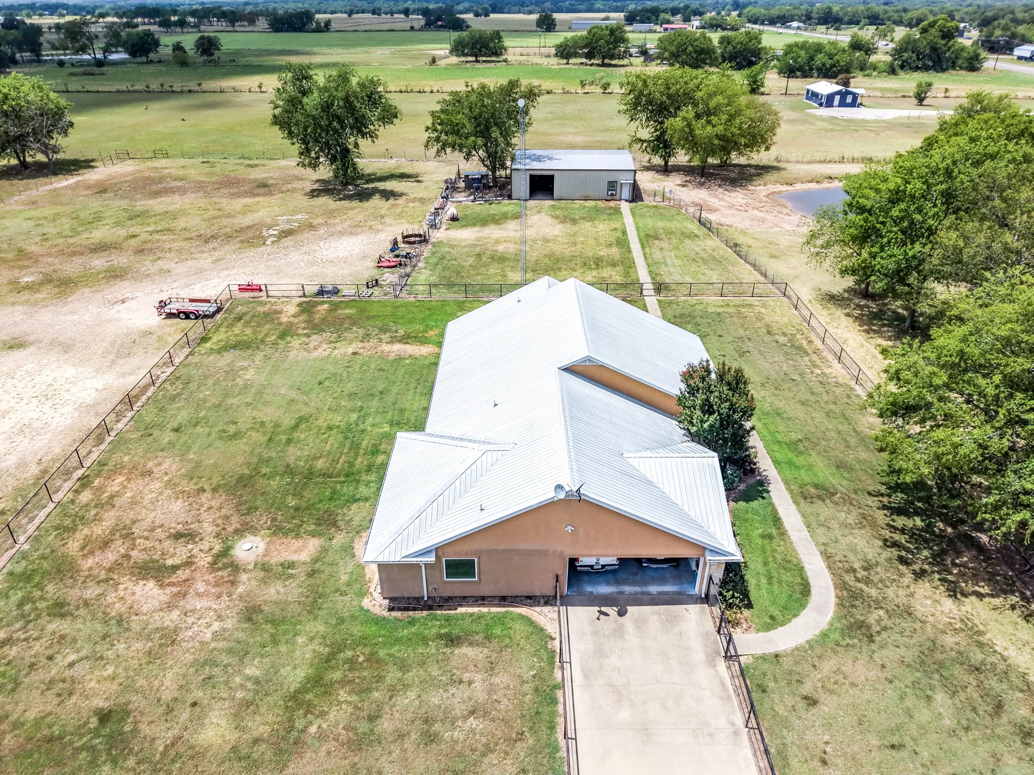Expansive property featuring a metal roof, attached carport, detached metal building, and a fenced perimeter