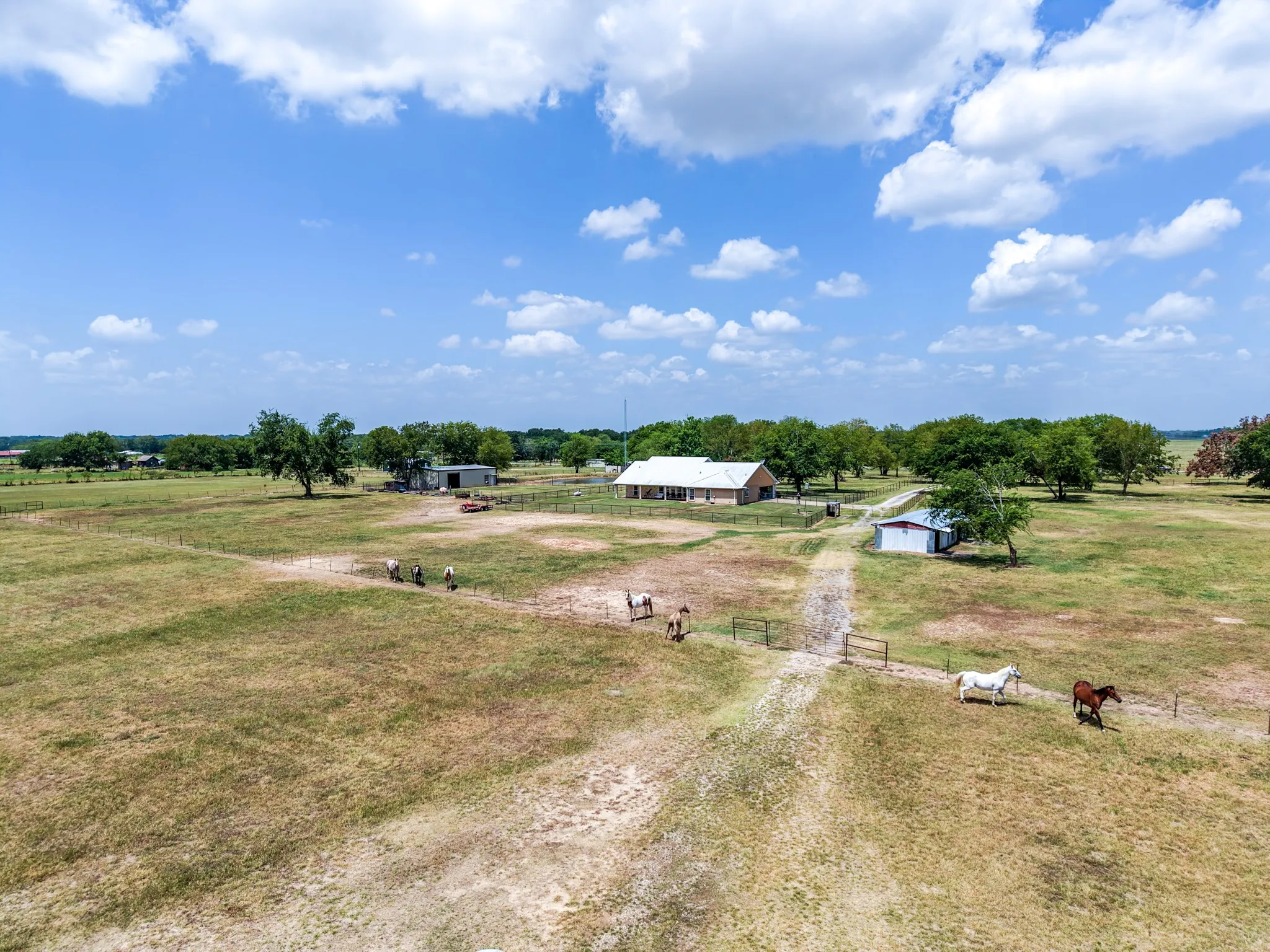 Expansive rural property featuring a single-story residence, multiple outbuildings, and extensive open land