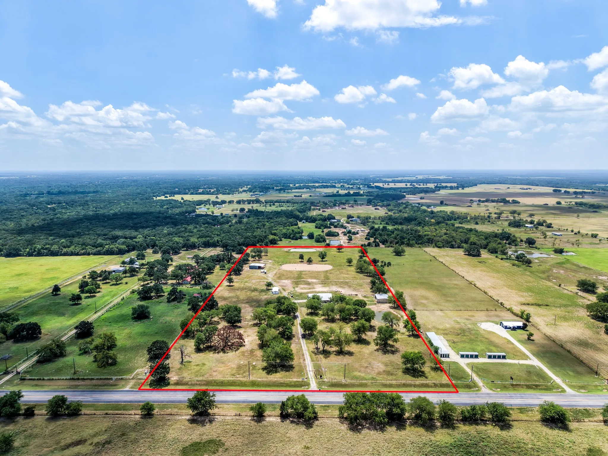Expansive property featuring multiple structures, open fields, and mature trees