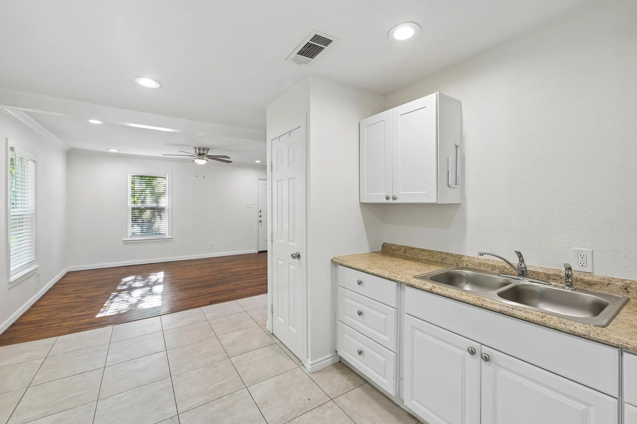 White cabinetry with silver hardware, dual basin stainless steel sink, and light-toned countertop